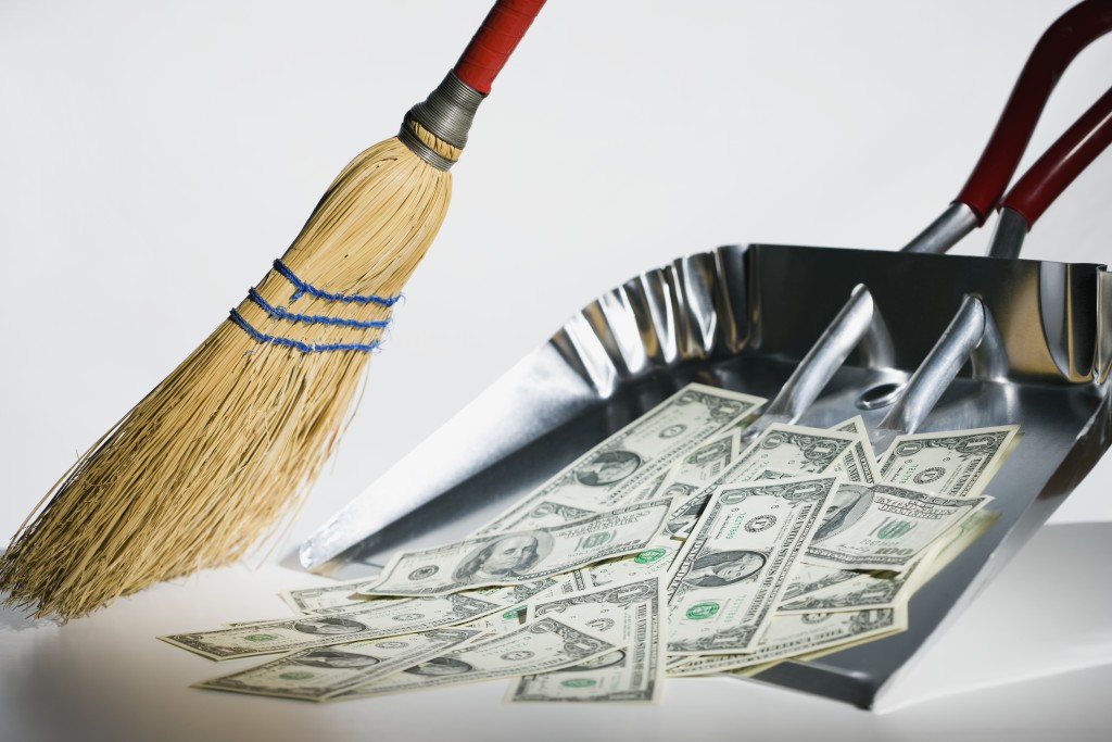 Sweeping US currency into dust pan --- Image by © Steve Hix/Somos Images/Corbis